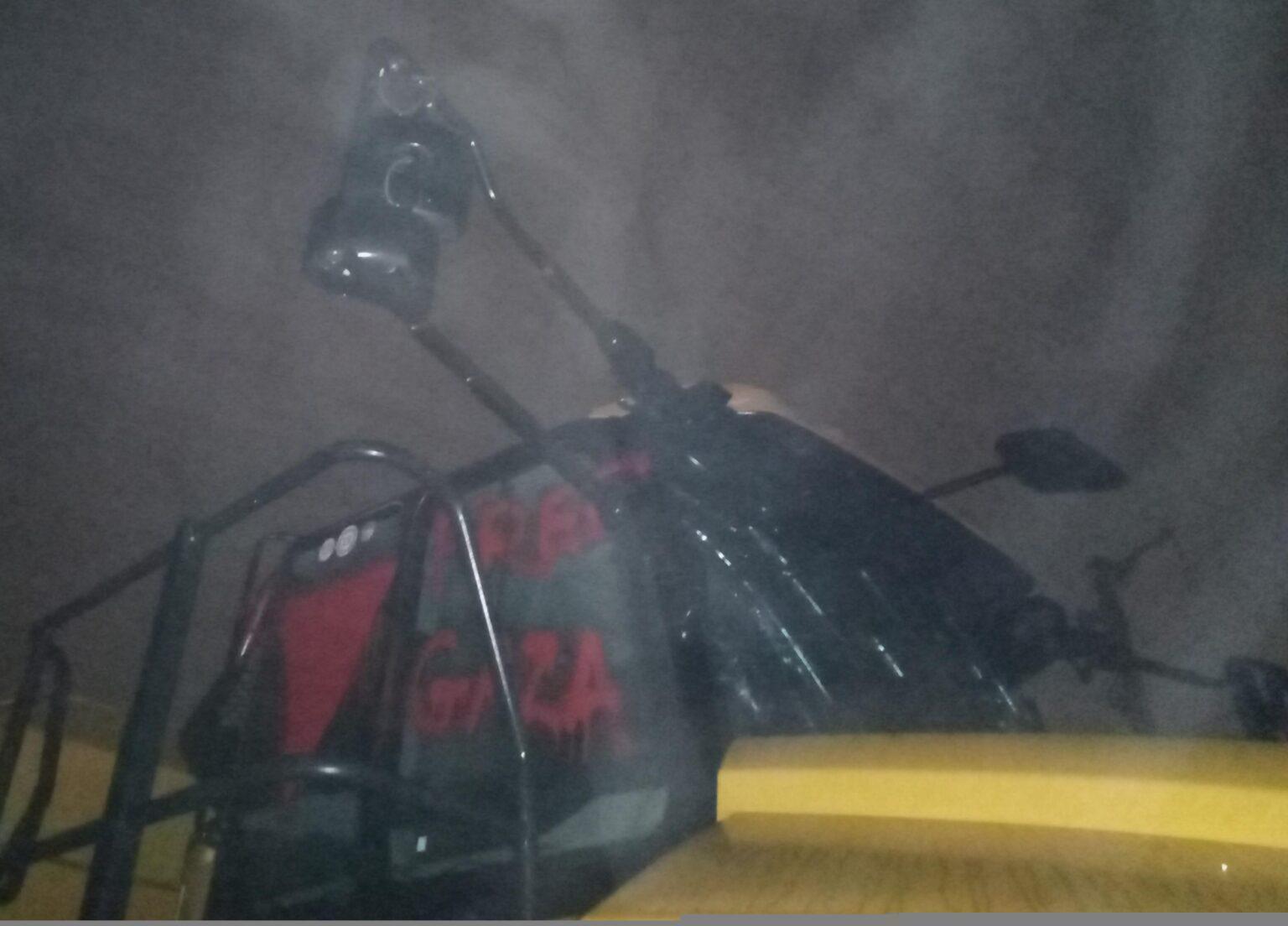 A vandalized CAT machine. The front window is smashed and graffiti on the side windows reads "FREE GAZA" with a red downward triangle.